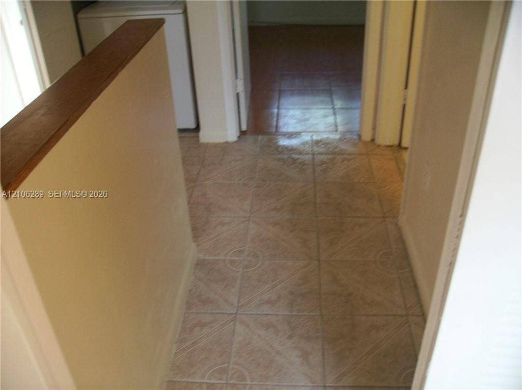 Square-tile flooring with textured detail, complemented by a half-wall featuring a stained wood cap