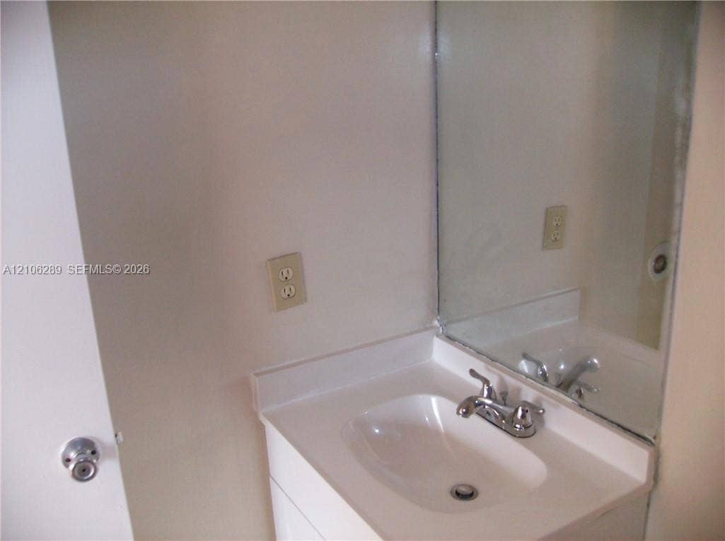 Vanity featuring a seamless integrated countertop and sink, polished chrome dual-handle faucet, and wall-mounted mirror