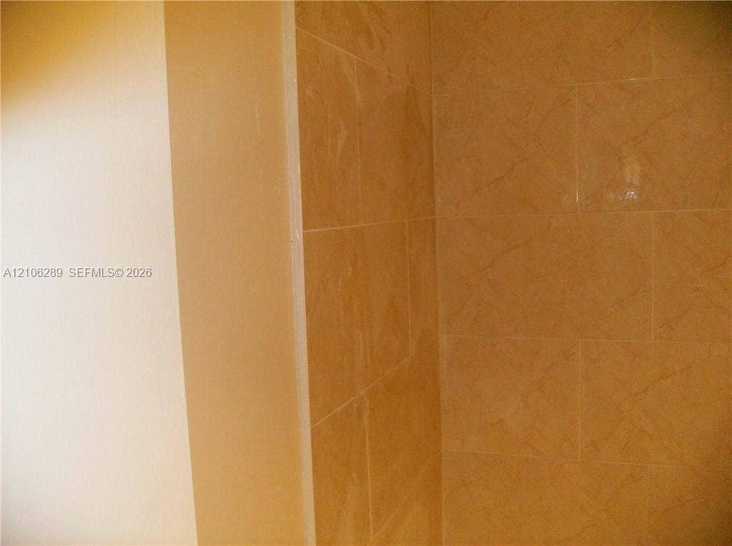 Neutral-toned wall finish with floor-to-ceiling tile surround featuring a subtle textured pattern