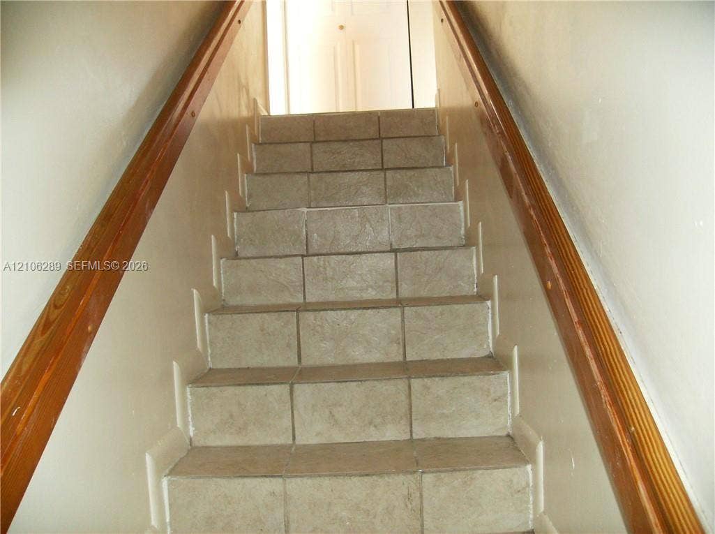 Staircase featuring tile treads and dual wood-finish handrails