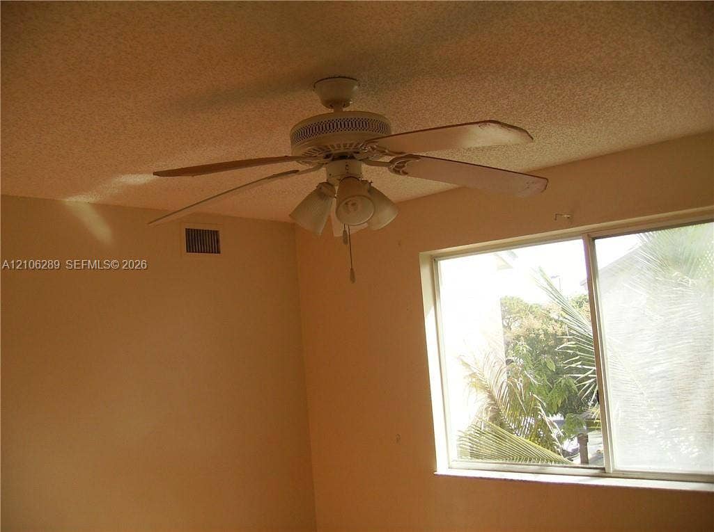 Ceiling-mounted fan with integrated multi-bulb light fixture and sliding window with exterior greenery