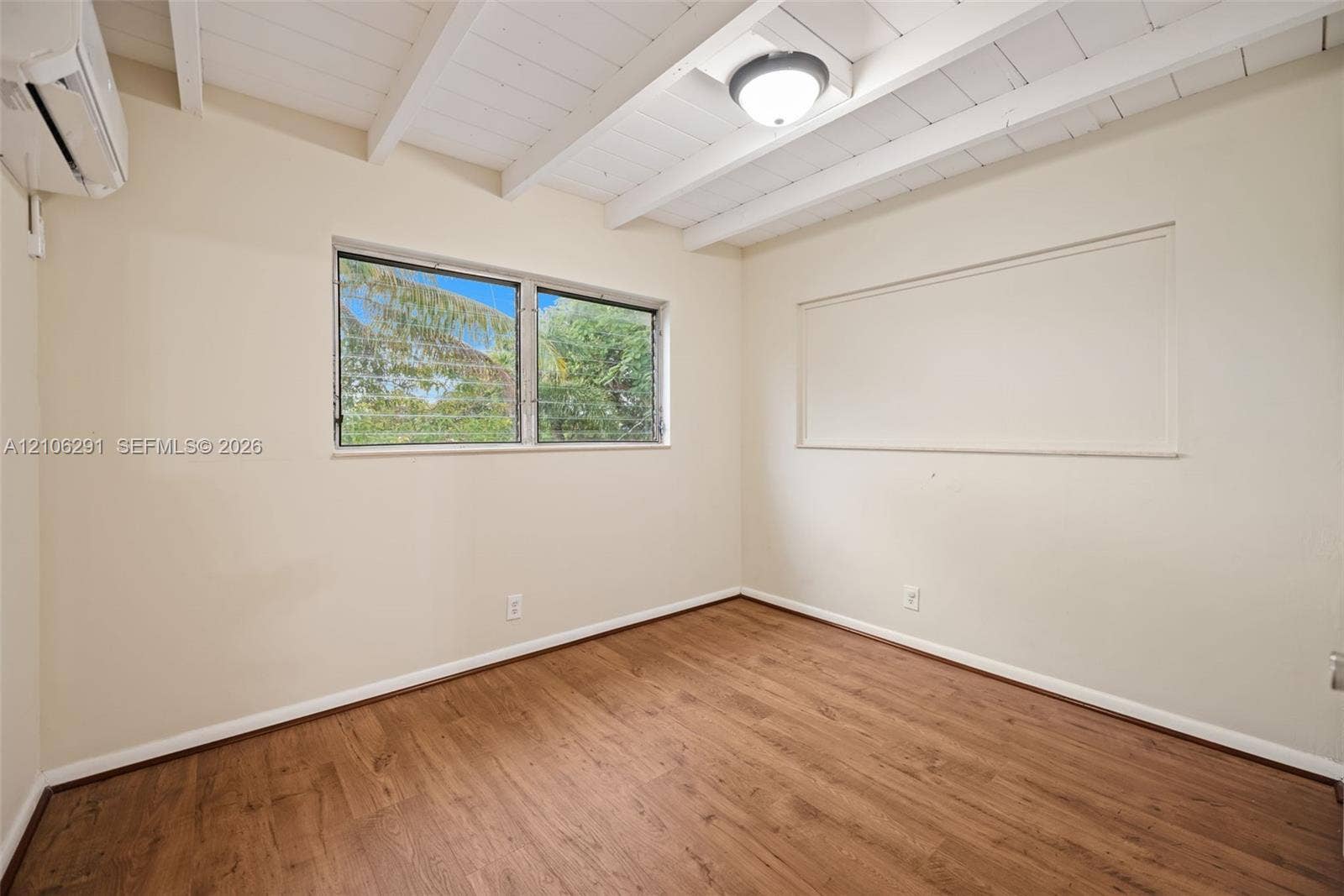 Exposed beam ceiling, wood-finish flooring, wall-mounted air conditioning unit, and dual-pane windows