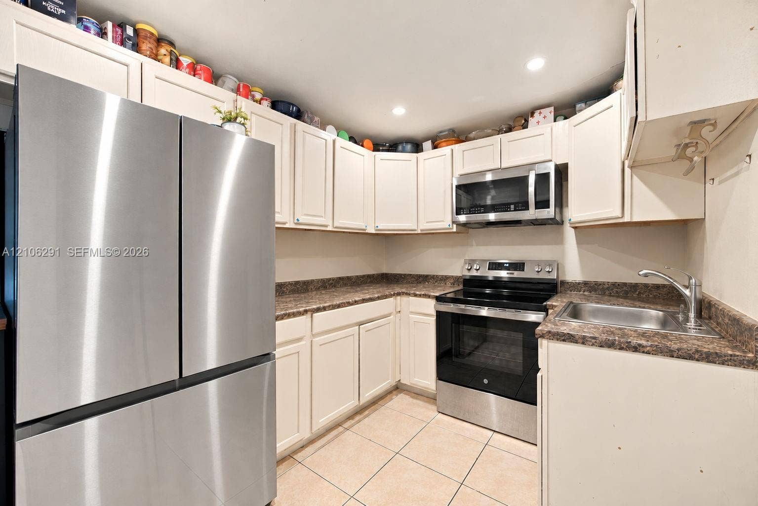 Kitchen featuring white cabinetry, stainless steel appliances, dark-toned laminate countertops, and tile flooring
