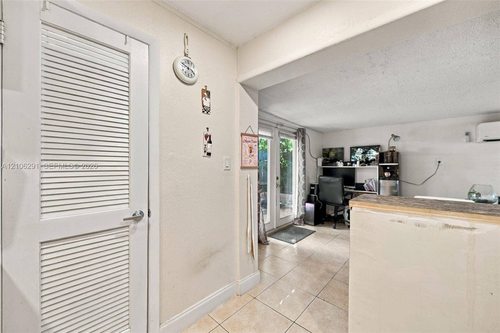 Interior featuring tiled flooring, a louvered-panel door, and glass-paned double doors with exterior exposure