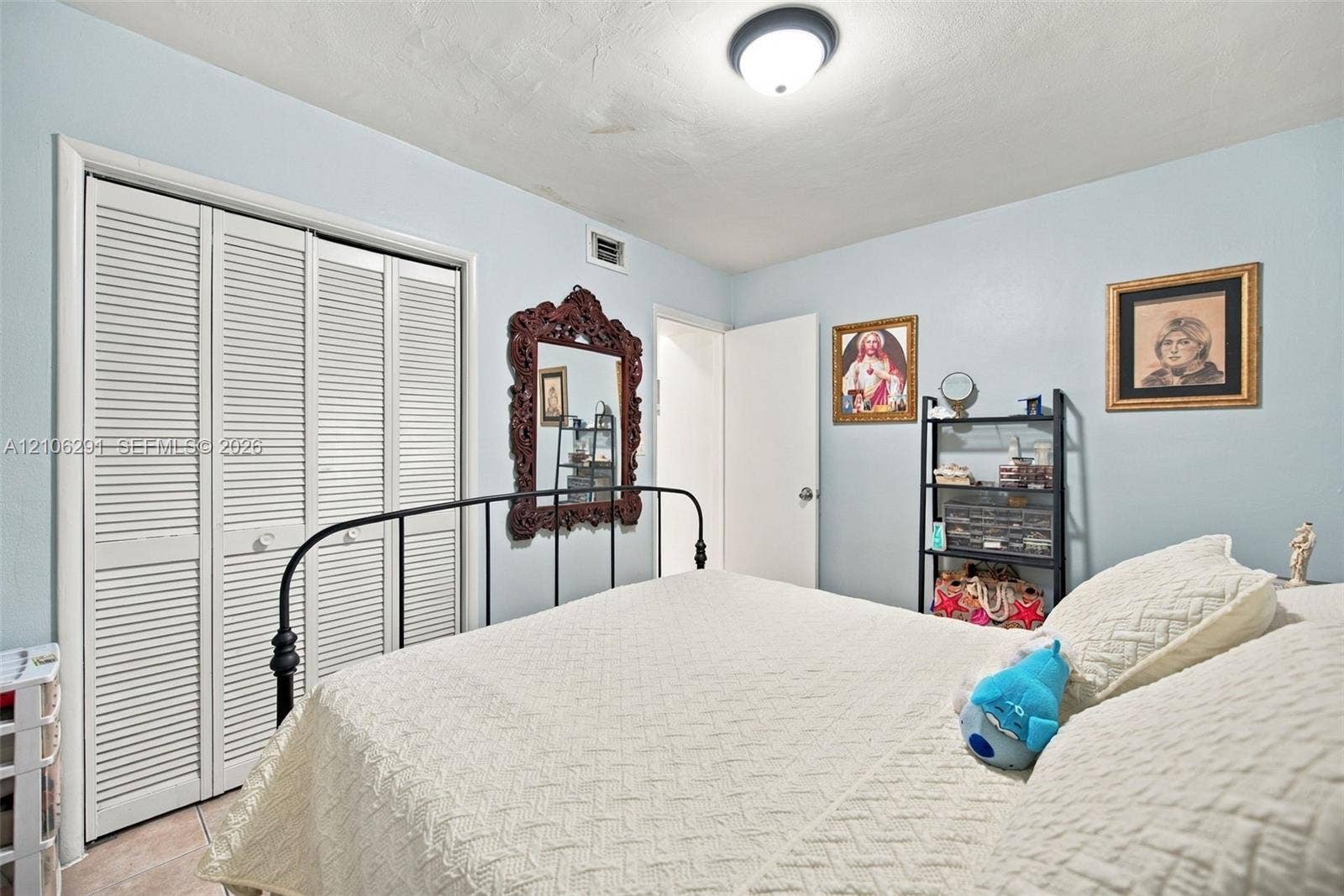 Room featuring light blue walls, white louvered-panel closet doors, and a flush-mount ceiling light fixture