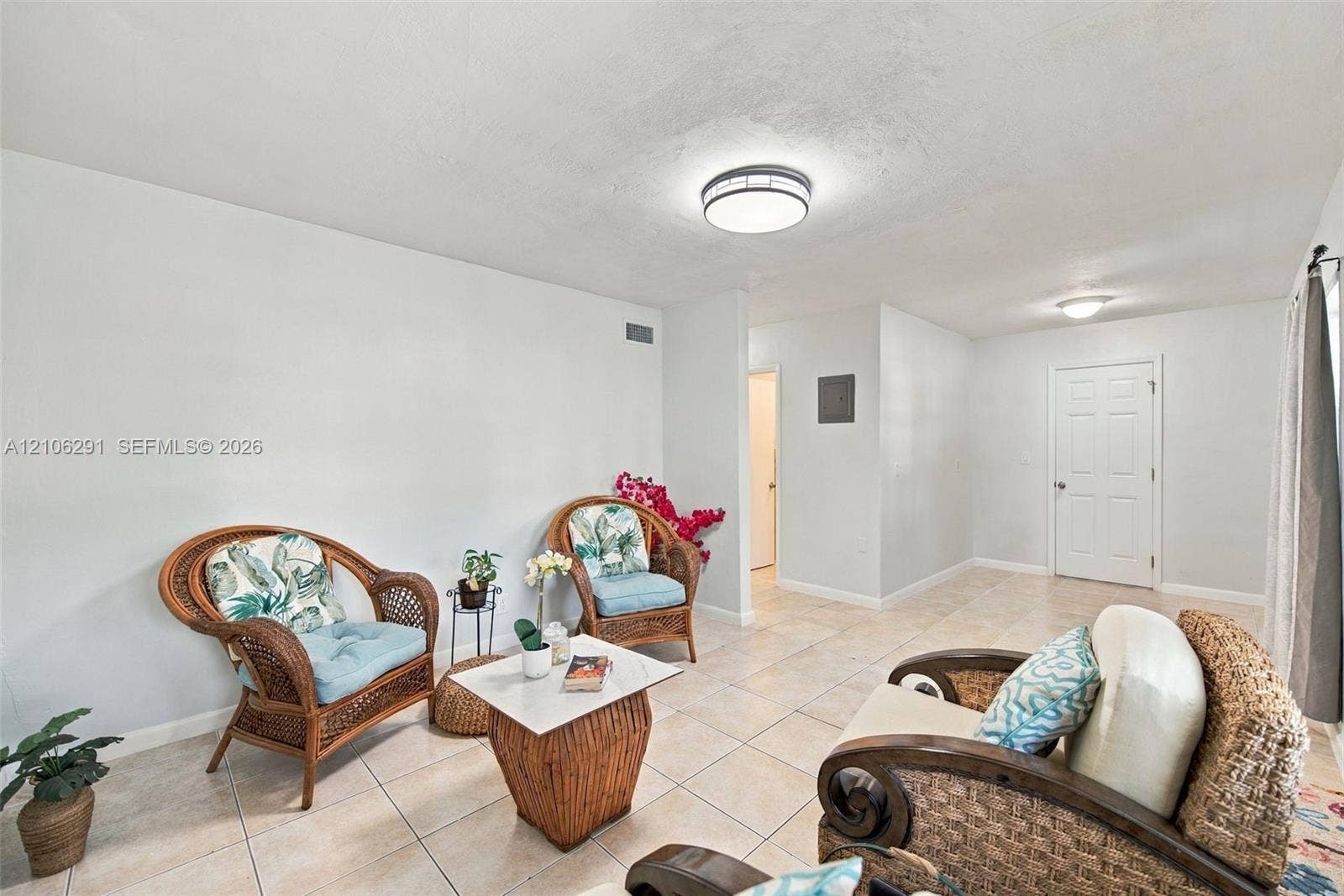 Neutral interior space featuring light-toned tile flooring, flush-mount ceiling lighting, and a six-panel interior door