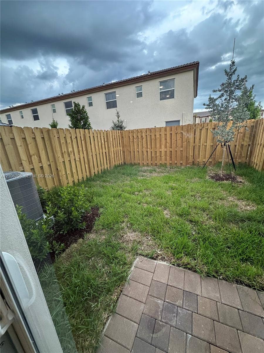 12103 NW 24th Place, #12103, Miami, Miami, FL 33167 Private backyard featuring a paved patio, grass lawn, wood privacy fencing, and landscaping