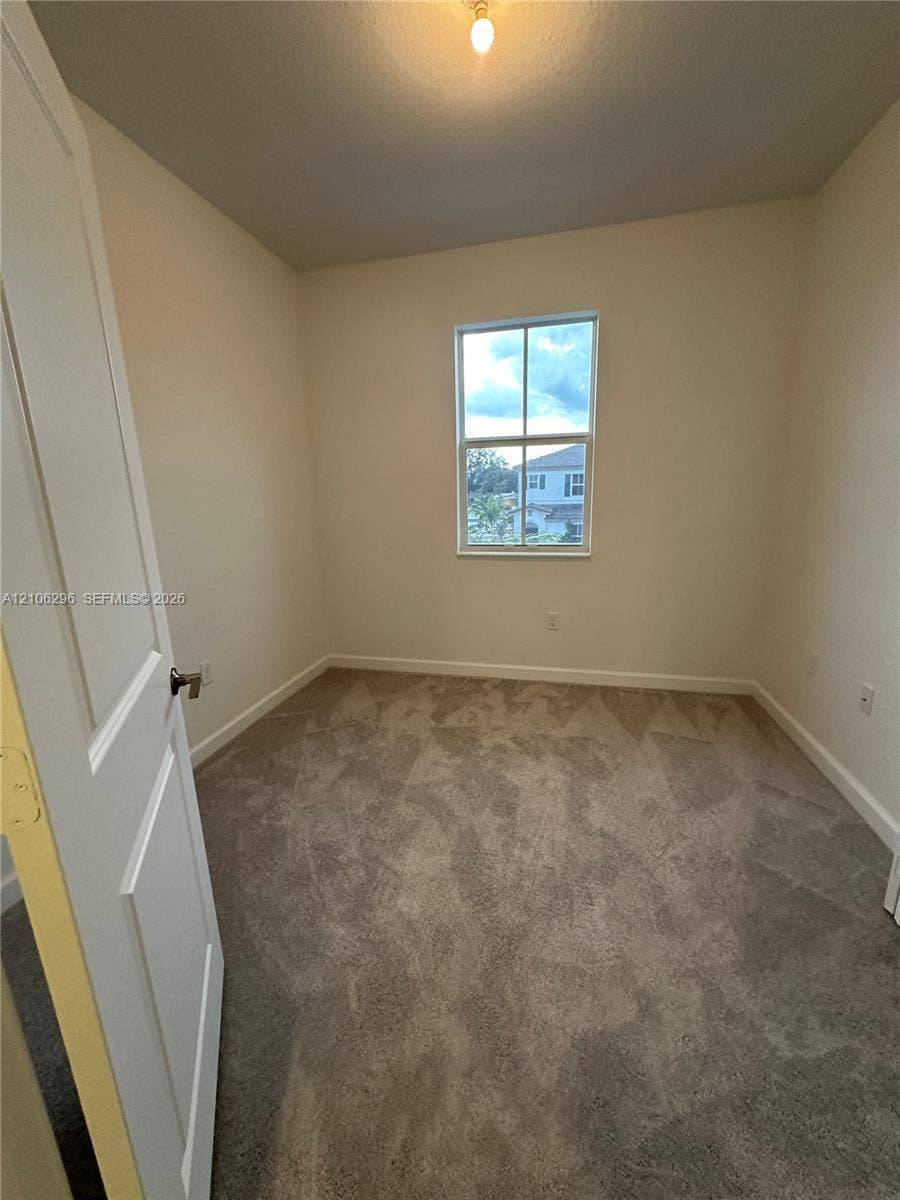 12103 NW 24th Place, #12103, Miami, Miami, FL 33167 Neutral-toned interior space featuring wall-to-wall carpeting, a single-hung window with a muntin grid, and a raised-panel interior door