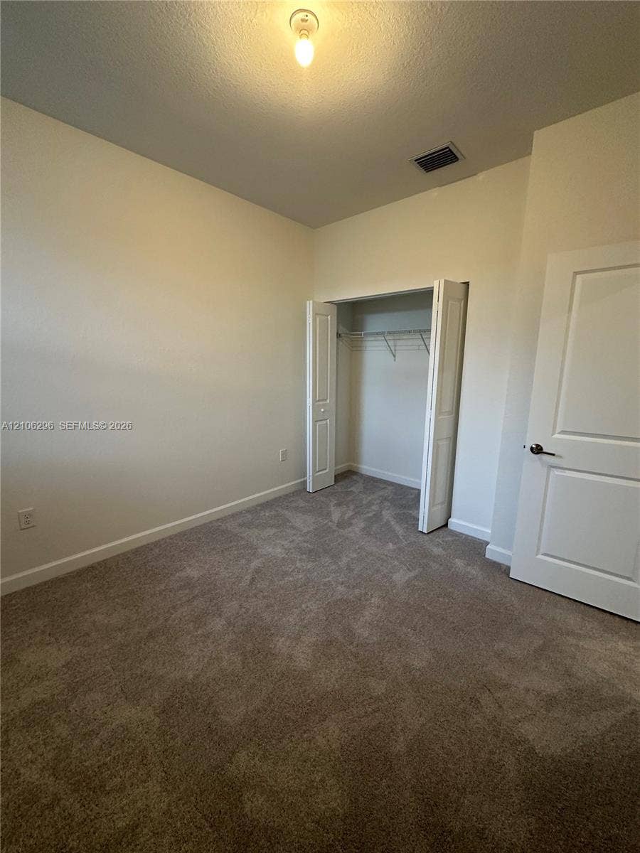 12103 NW 24th Place, #12103, Miami, Miami, FL 33167 Neutral-toned carpeted flooring, wall-mounted interior door, and bi-fold closet doors with integrated wire shelving