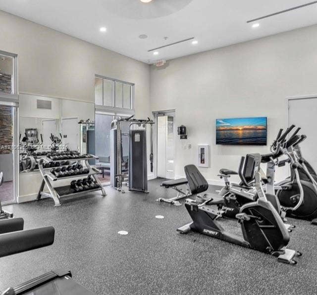 12103 NW 24th Place, #12103, Miami, Miami, FL 33167 Fitness area featuring high ceilings, recessed lighting, expansive wall-to-wall mirrors, and durable rubberized flooring