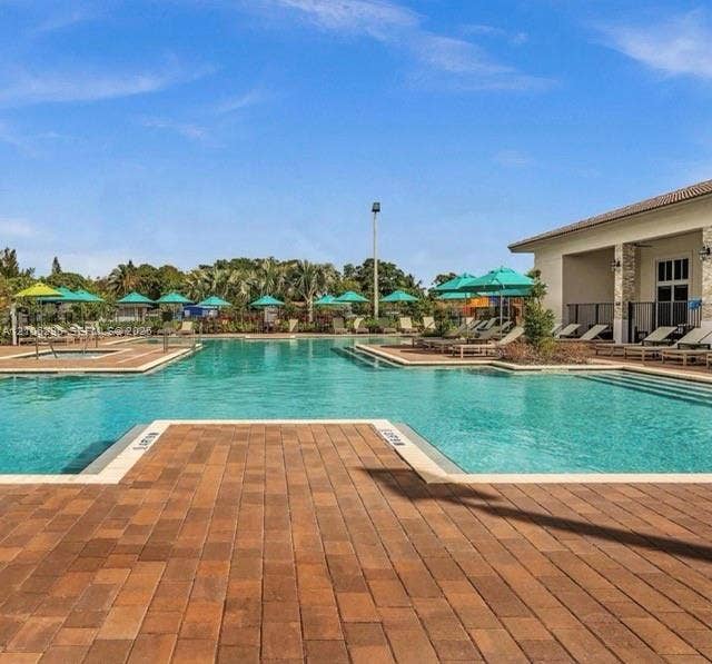 12103 NW 24th Place, #12103, Miami, Miami, FL 33167 Swimming pool featuring a paver deck, integrated spa, and exterior stone masonry