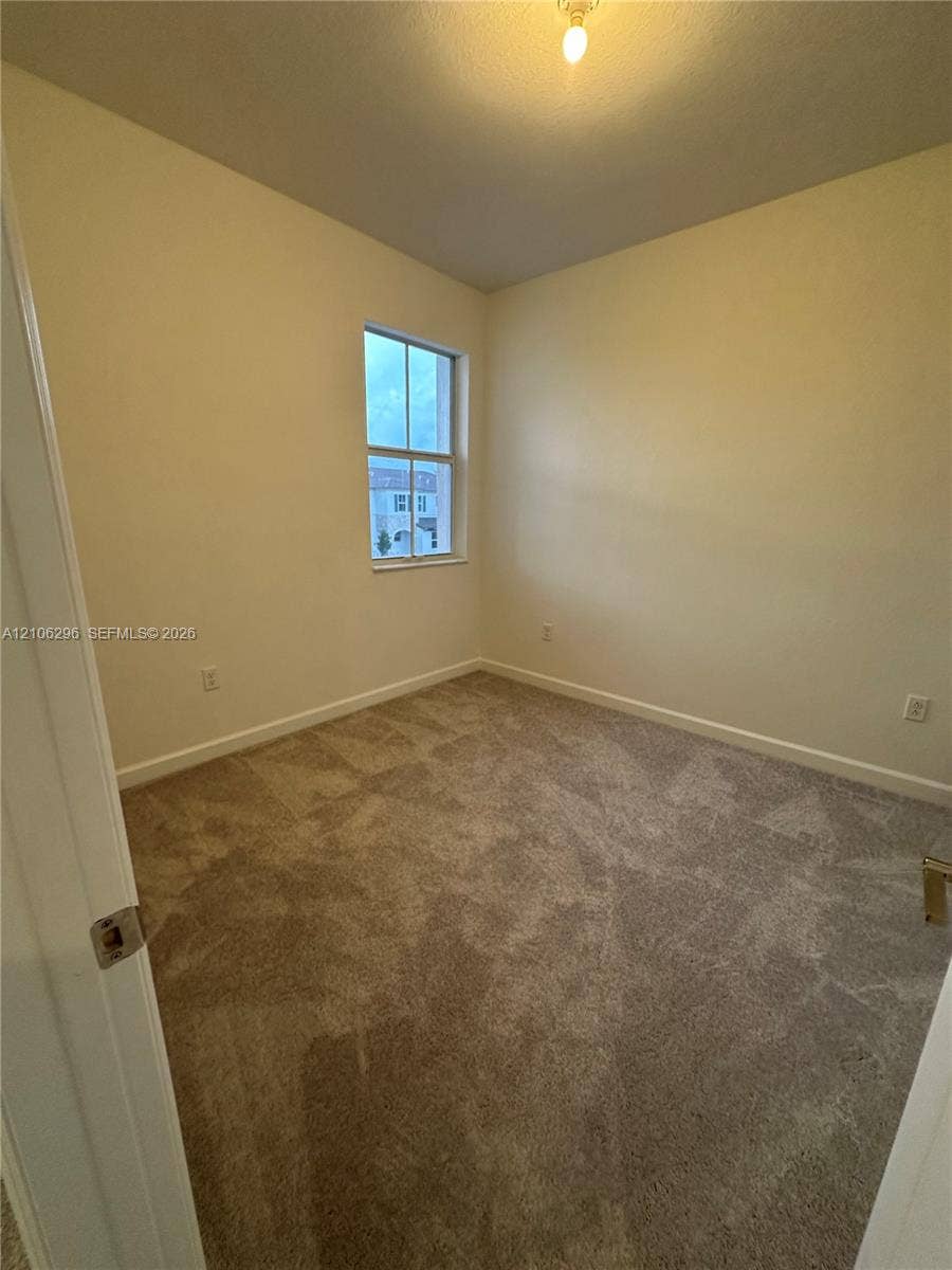 12103 NW 24th Place, #12103, Miami, Miami, FL 33167 Neutral interior room featuring plush wall-to-wall carpeting, a single-hung window with a muntin grid, and a ceiling-mounted light fixture