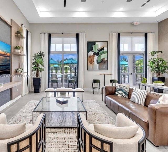 12103 NW 24th Place, #12103, Miami, Miami, FL 33167 Common area featuring a double-tray ceiling with recessed lighting, built-in wall shelving, expansive windows, and dual sets of glass-paneled doors opening to an exterior patio