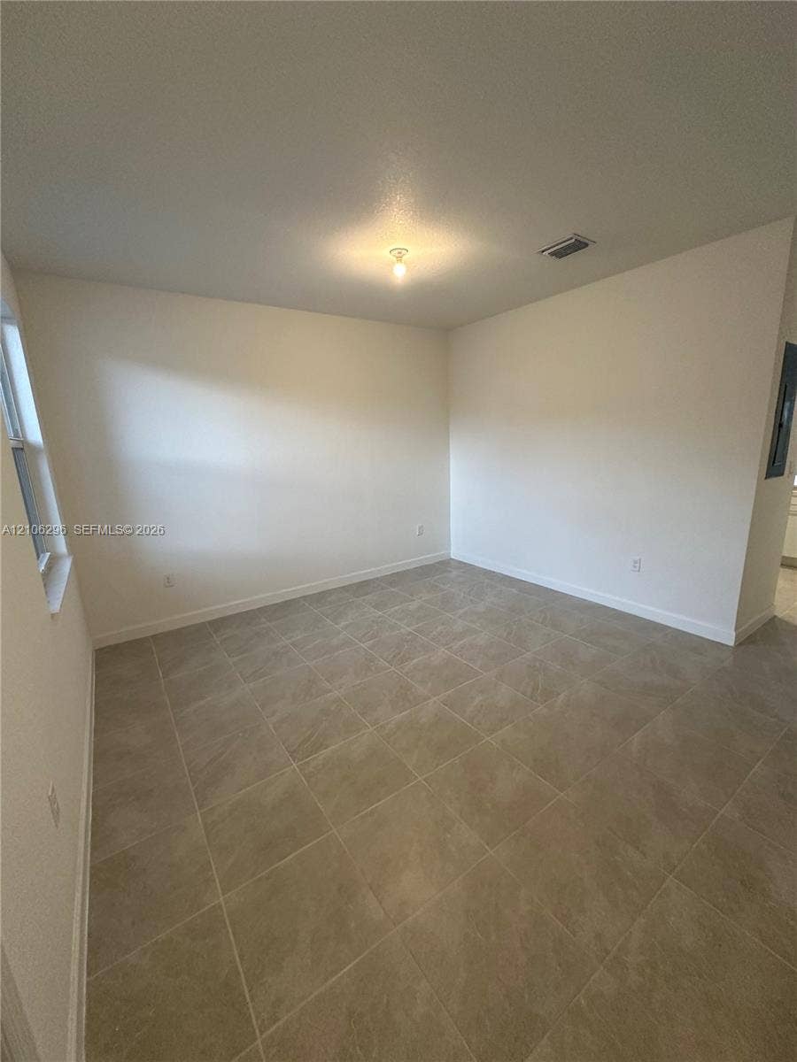 12103 NW 24th Place, #12103, Miami, Miami, FL 33167 Interior space featuring neutral wall tones, large-format tile flooring, a single-fixture ceiling light, and natural light from a window
