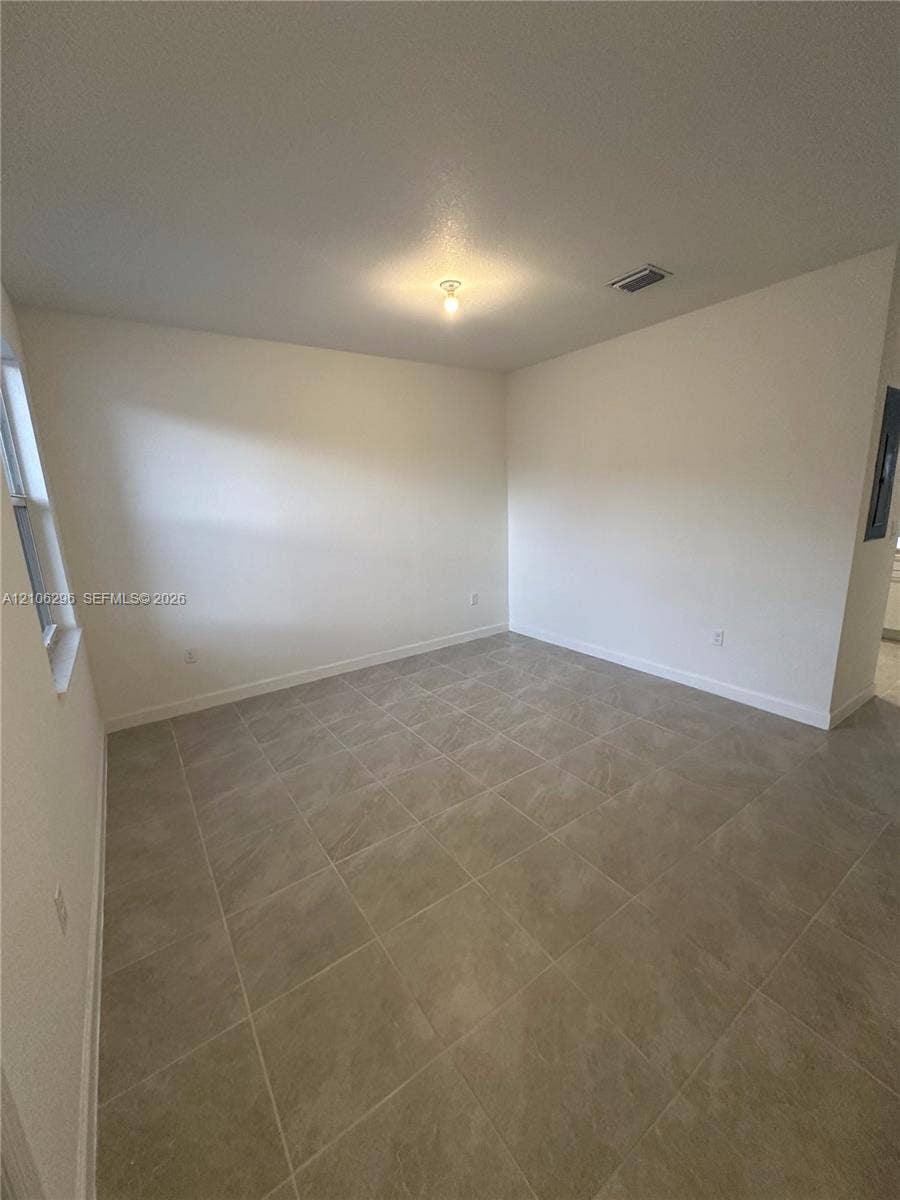 12103 NW 24th Place, #12103, Miami, Miami, FL 33167 Neutral-toned interior space featuring large-format ceramic tile flooring, neutral wall paint, and a single-light ceiling fixture