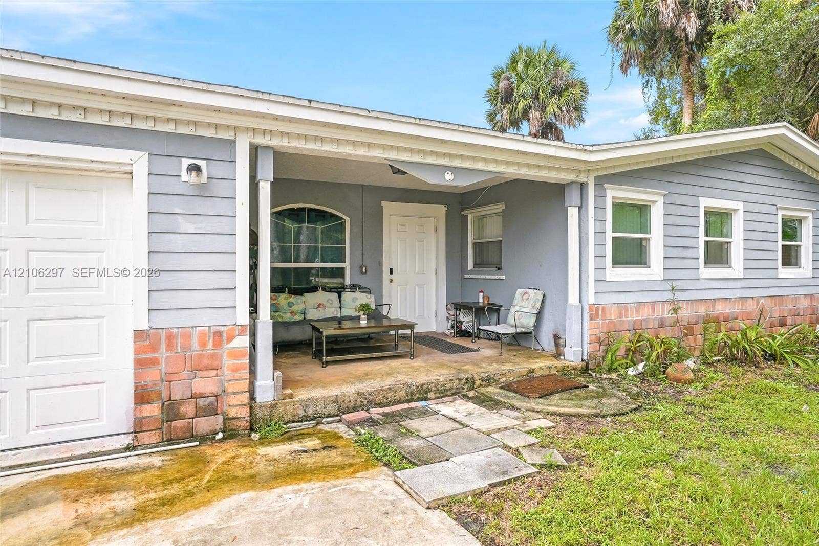 4810 Lakewood Park Drive, Fort Pierce, FL 34951 Exterior featuring blue horizontal siding, a partial brick facade, a covered entryway with structural posts, and a stone paver walkway