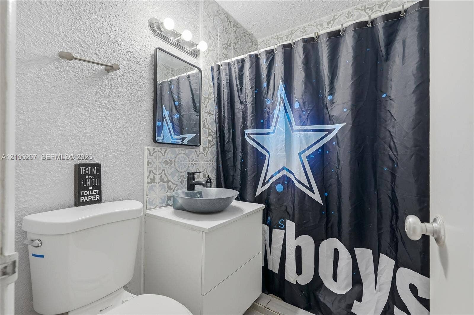4810 Lakewood Park Drive, Fort Pierce, FL 34951 Bathroom featuring a white vanity cabinet, a grey circular vessel sink, matte black faucet, rectangular framed mirror, and decorative patterned tile backsplash