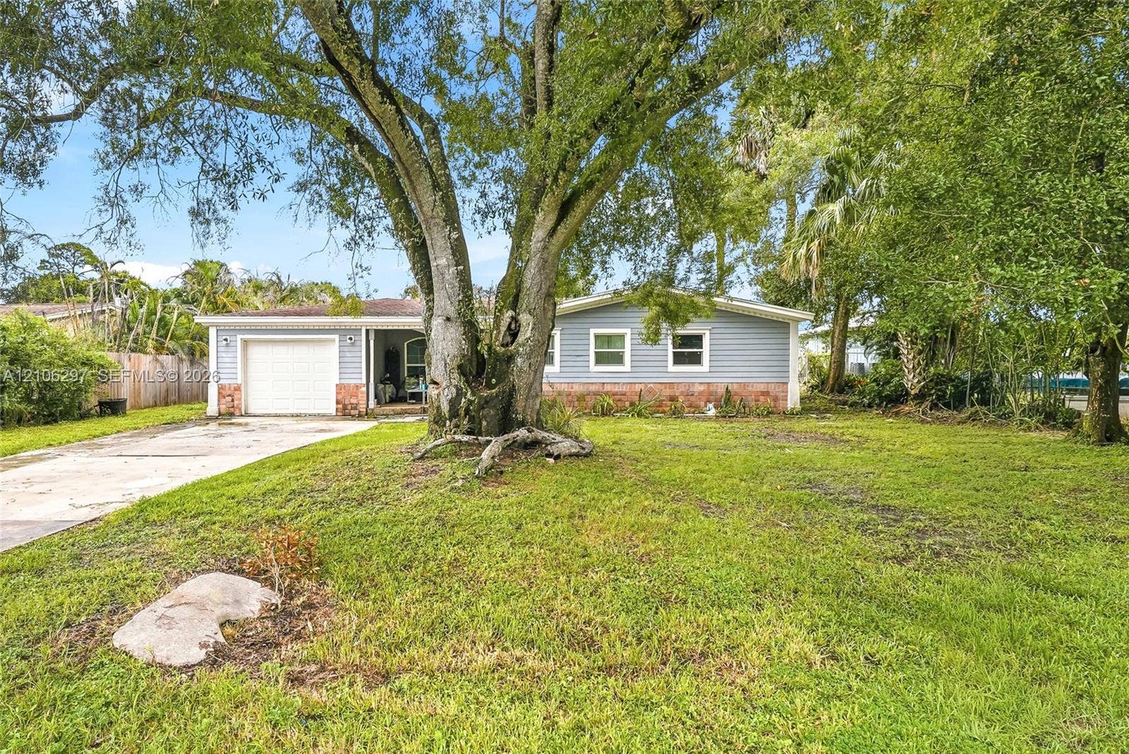 4810 Lakewood Park Drive, Fort Pierce, FL 34951 Exterior featuring horizontal lap siding, a brick facade base, a single-car garage, and a mature oak tree