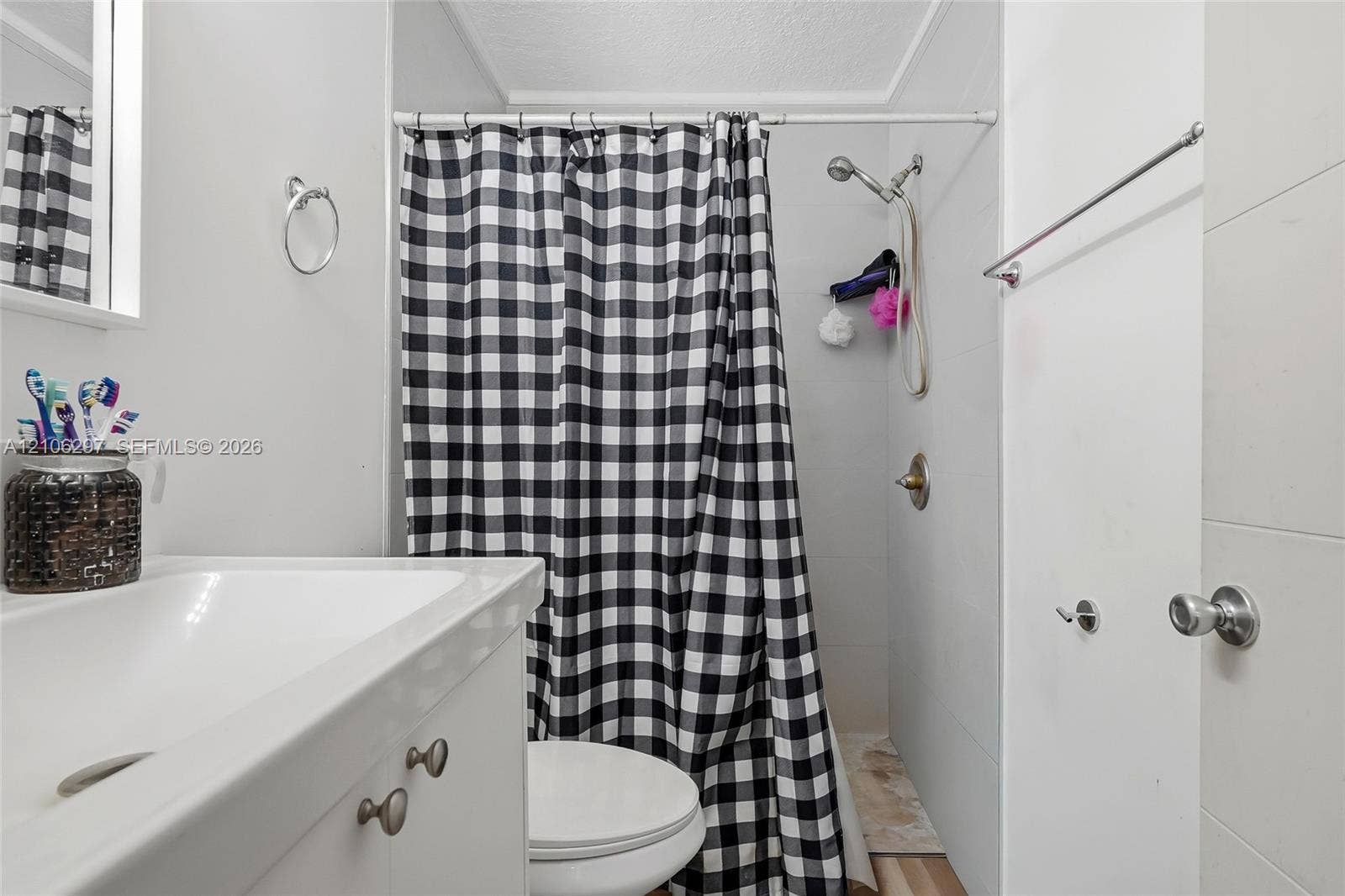 4810 Lakewood Park Drive, Fort Pierce, FL 34951 Bathroom featuring a white vanity cabinet, integrated sink, wall-mounted towel hardware, and a shower area with a handheld showerhead