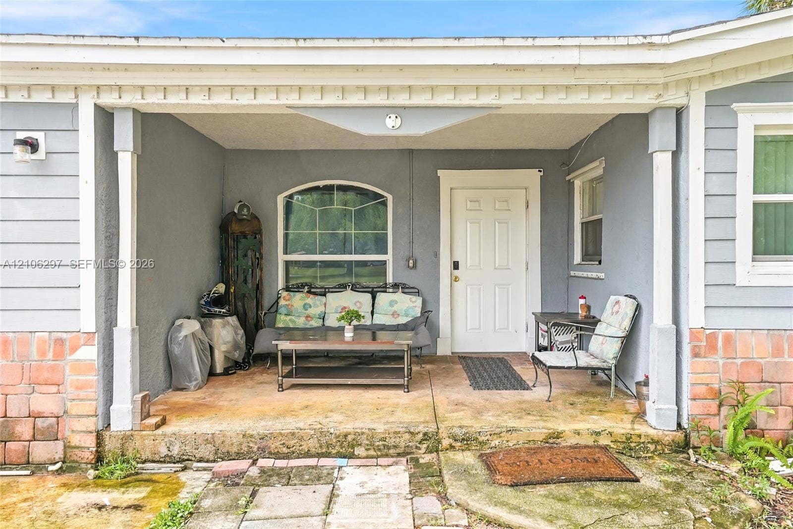 4810 Lakewood Park Drive, Fort Pierce, FL 34951 Covered front porch featuring lap siding, brick masonry detailing, square support columns, and an arched window