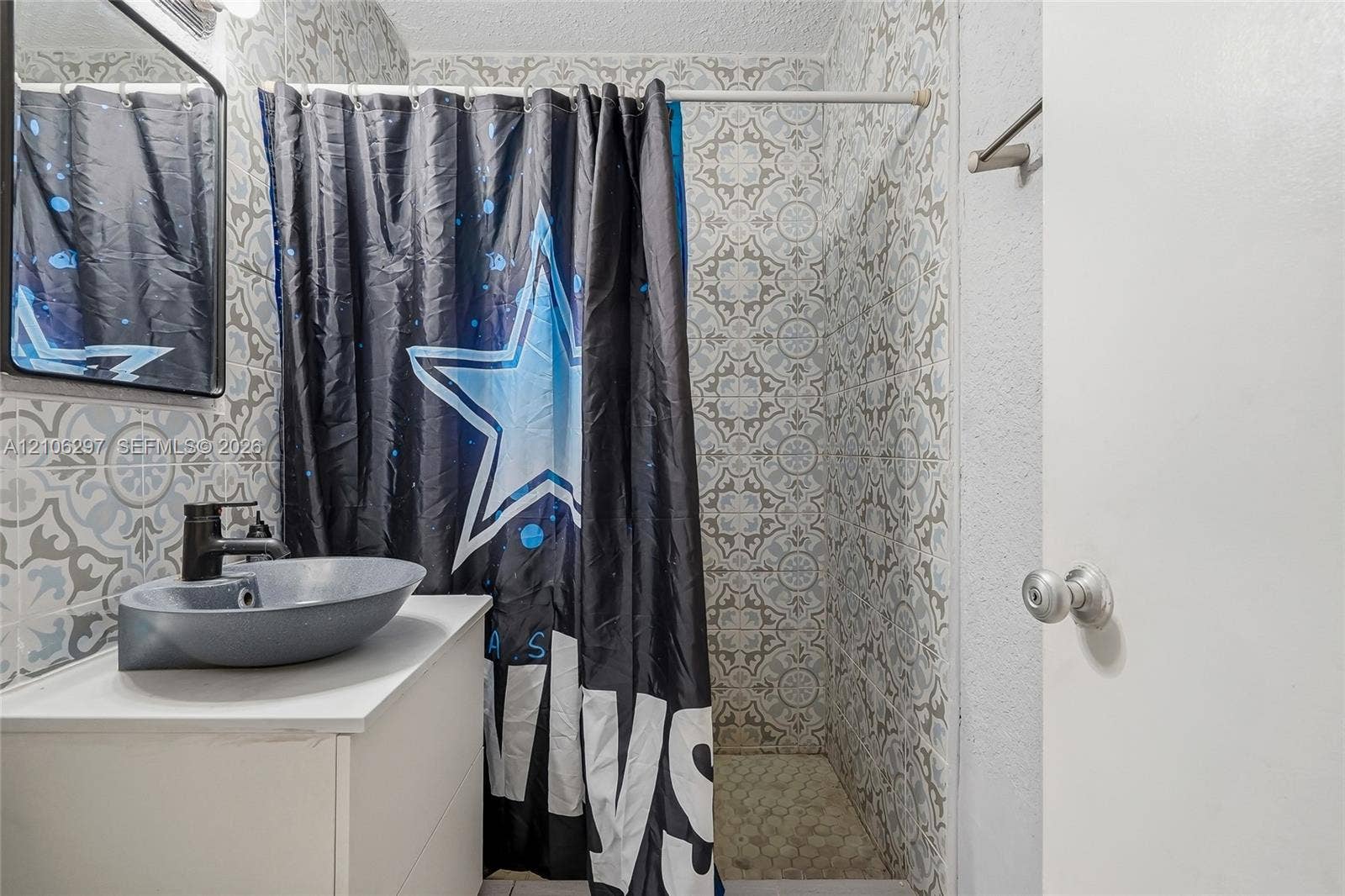 4810 Lakewood Park Drive, Fort Pierce, FL 34951 Bathroom featuring patterned wall tile, a white vanity cabinet, and a grey vessel sink with a black faucet