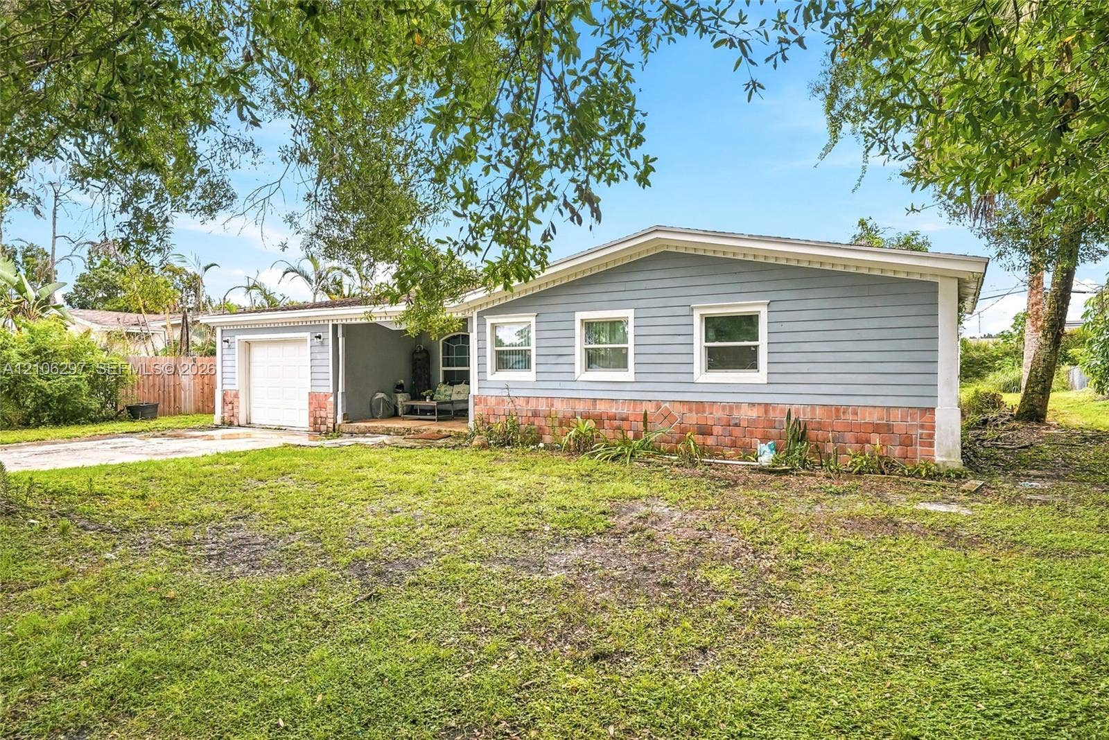 4810 Lakewood Park Drive, Fort Pierce, FL 34951 Single-story residence featuring blue horizontal siding, a red brick veneer base, a covered entryway, an attached garage, and a concrete driveway