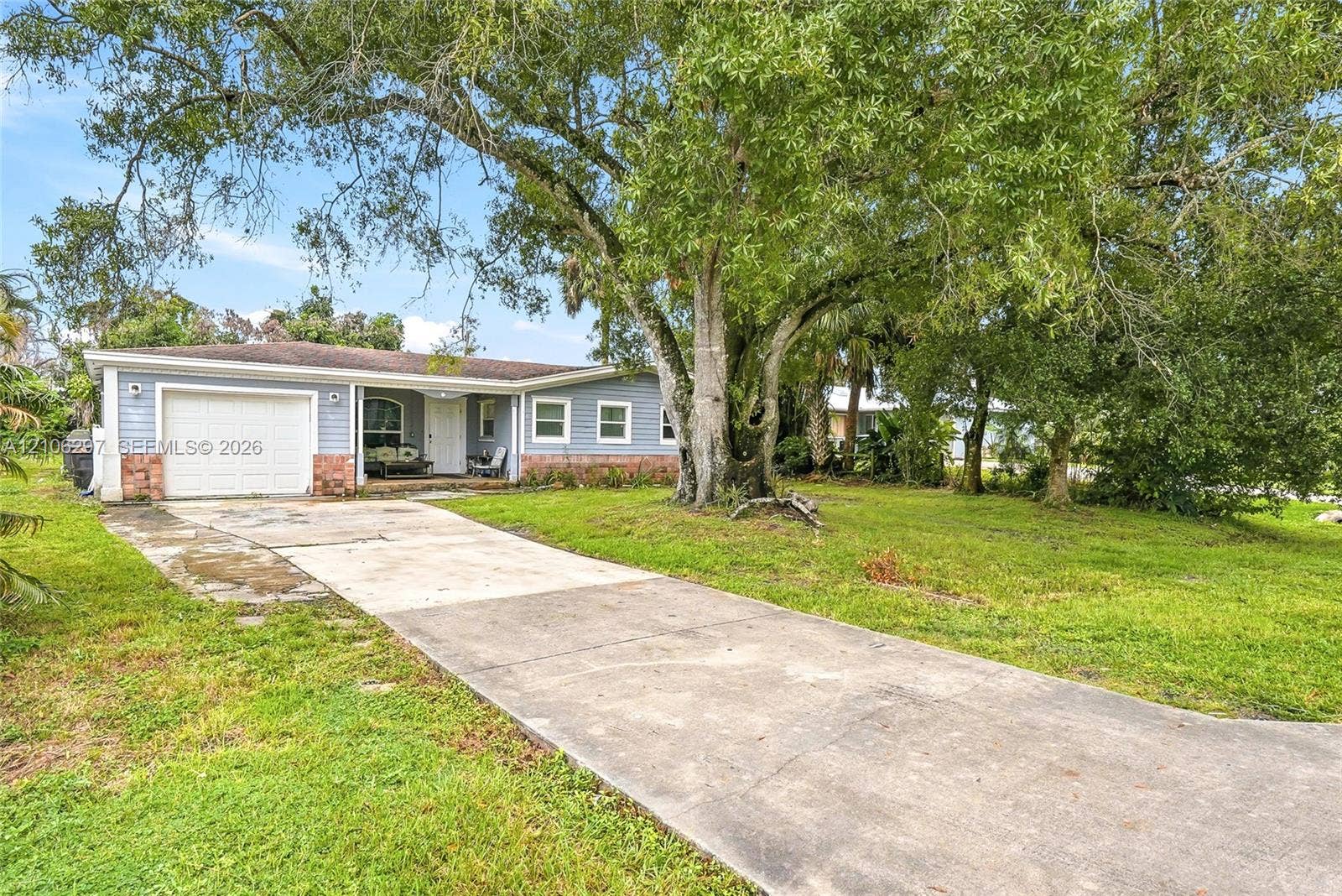 4810 Lakewood Park Drive, Fort Pierce, FL 34951 Single-story residence featuring horizontal lap siding, stone veneer accents, a one-car garage, concrete driveway, and mature landscaping