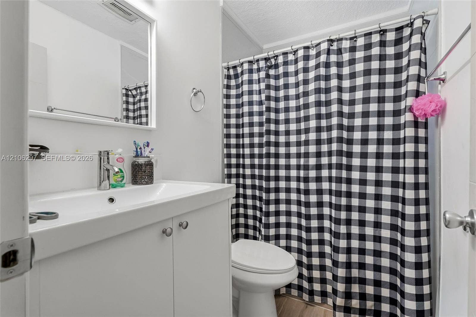 4810 Lakewood Park Drive, Fort Pierce, FL 34951 White vanity featuring a rectangular basin with a single-handle chrome faucet, a wall-mounted mirror, and a combination tub-shower with a chrome-finish shower rod