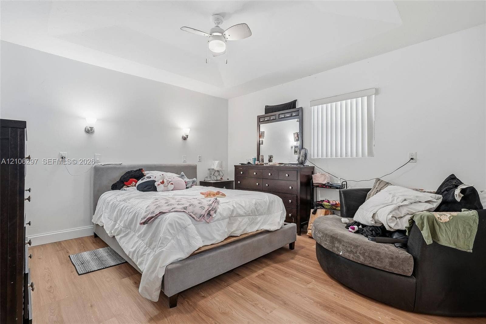 4810 Lakewood Park Drive, Fort Pierce, FL 34951 Tray ceiling featuring a central ceiling fan with integrated lighting, wood-finish flooring, and dual wall-mounted light fixtures