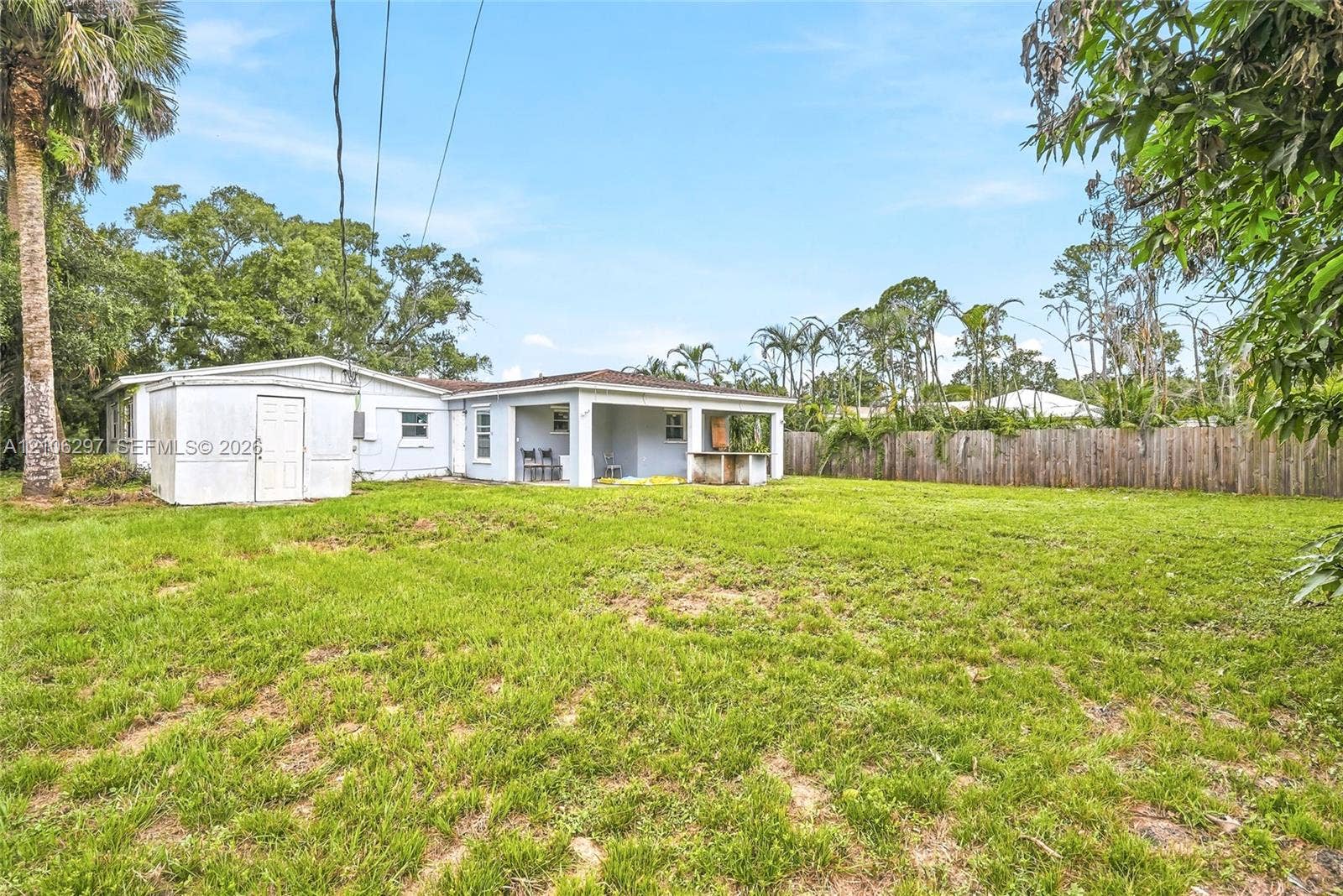 4810 Lakewood Park Drive, Fort Pierce, FL 34951 Expansive backyard featuring a covered patio, built-in outdoor masonry counter, detached storage structure, and perimeter wood fencing