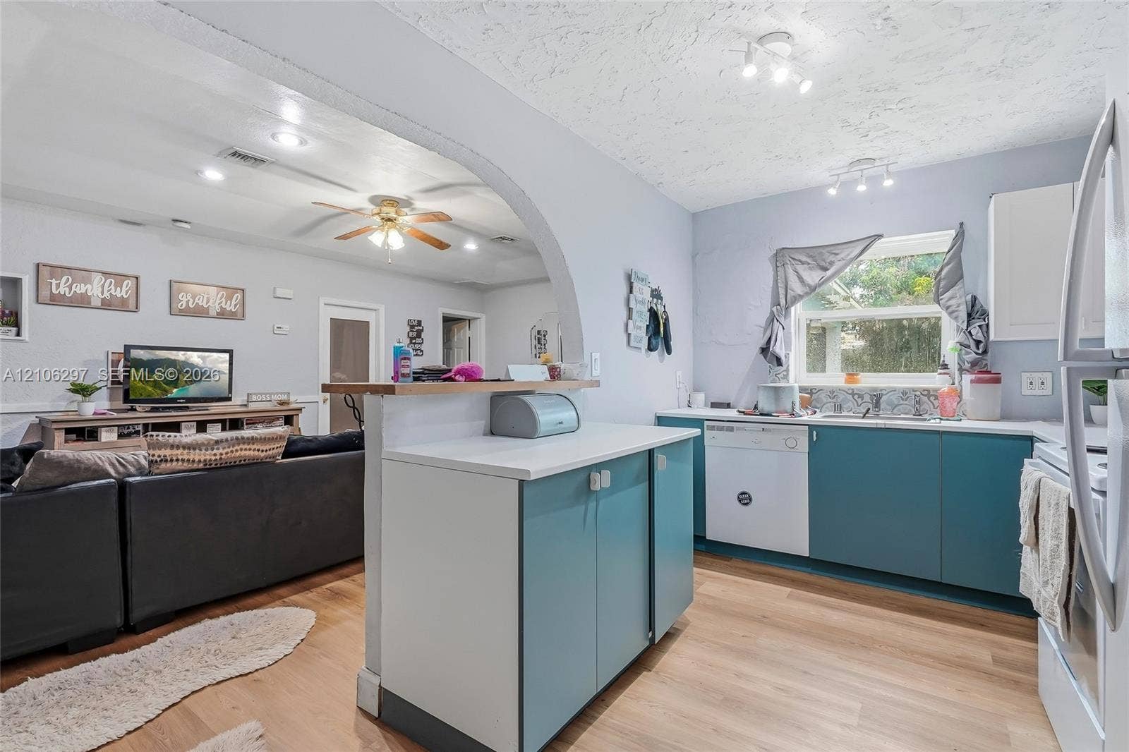 4810 Lakewood Park Drive, Fort Pierce, FL 34951 Kitchen featuring teal cabinetry, white countertops, wood-finish flooring, a decorative arched entryway, and integrated ceiling track lighting