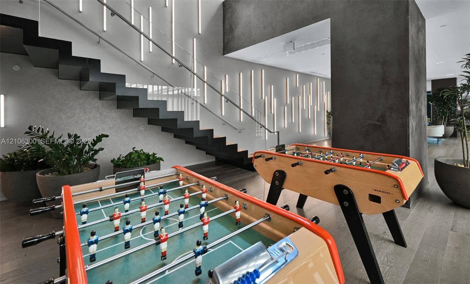 480 NE 31st Street, #1005, Miami, Miami, FL 33137 Floating staircase with black steel stringers, integrated vertical wall lighting, wood-finish flooring, and textured dark accent pillar