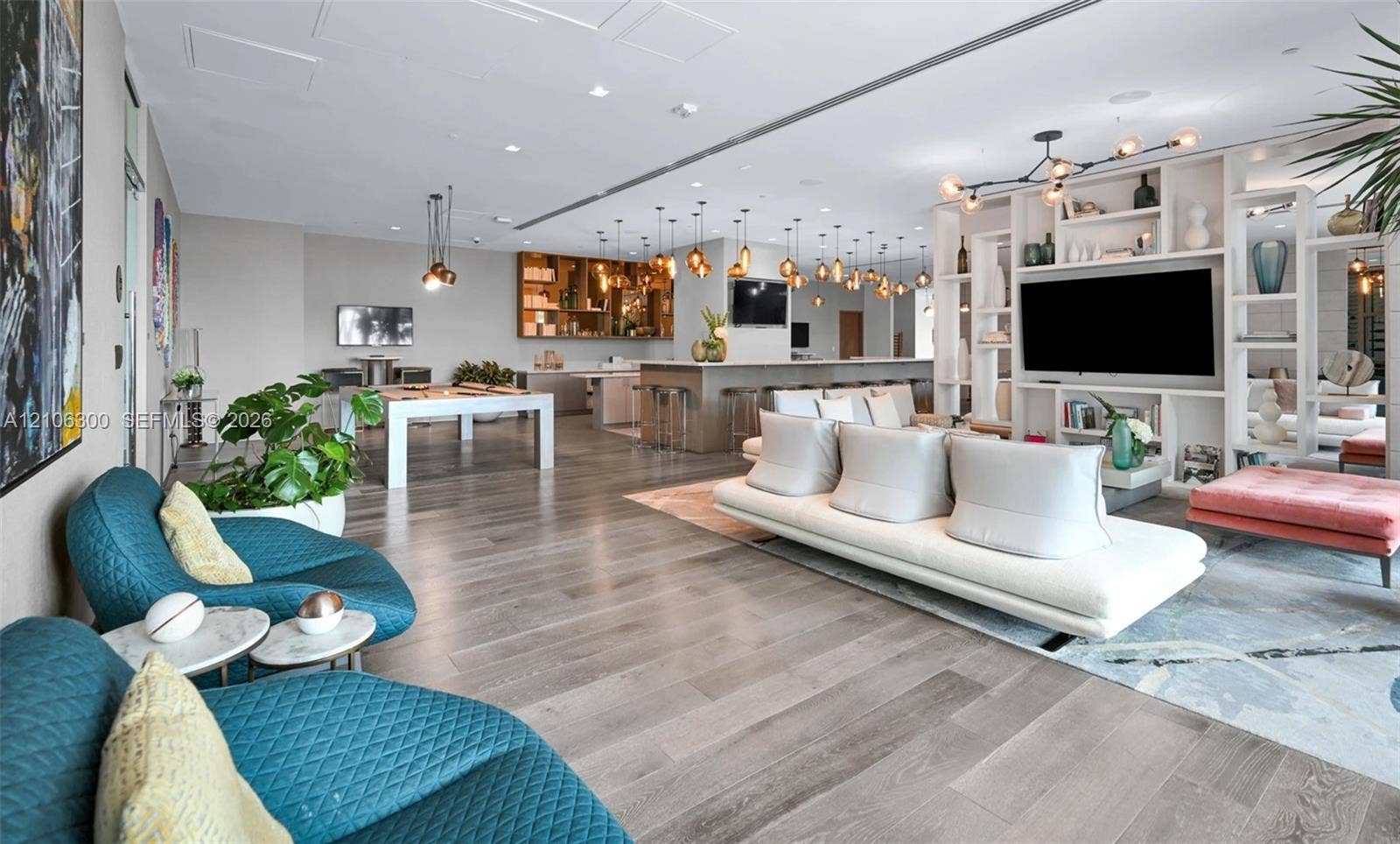 480 NE 31st Street, #1005, Miami, Miami, FL 33137 Open-concept interior featuring wood-finish flooring, floor-to-ceiling built-in shelving, a kitchen island with bar seating, and recessed lighting