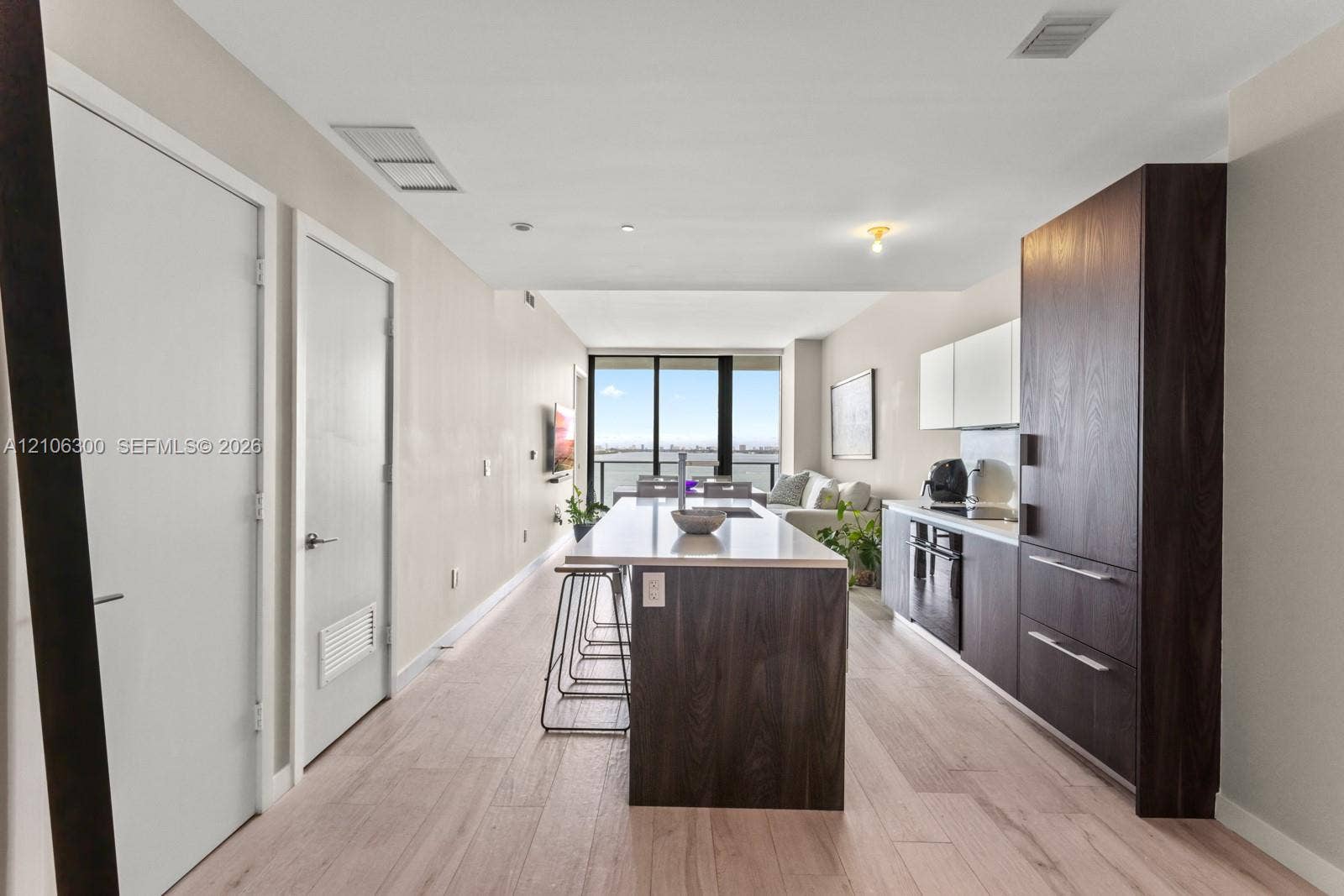 480 NE 31st Street, #1005, Miami, Miami, FL 33137 Kitchen featuring a central island with a solid-surface countertop, dark wood-finish cabinetry, built-in appliances, and light wood-finish flooring throughout