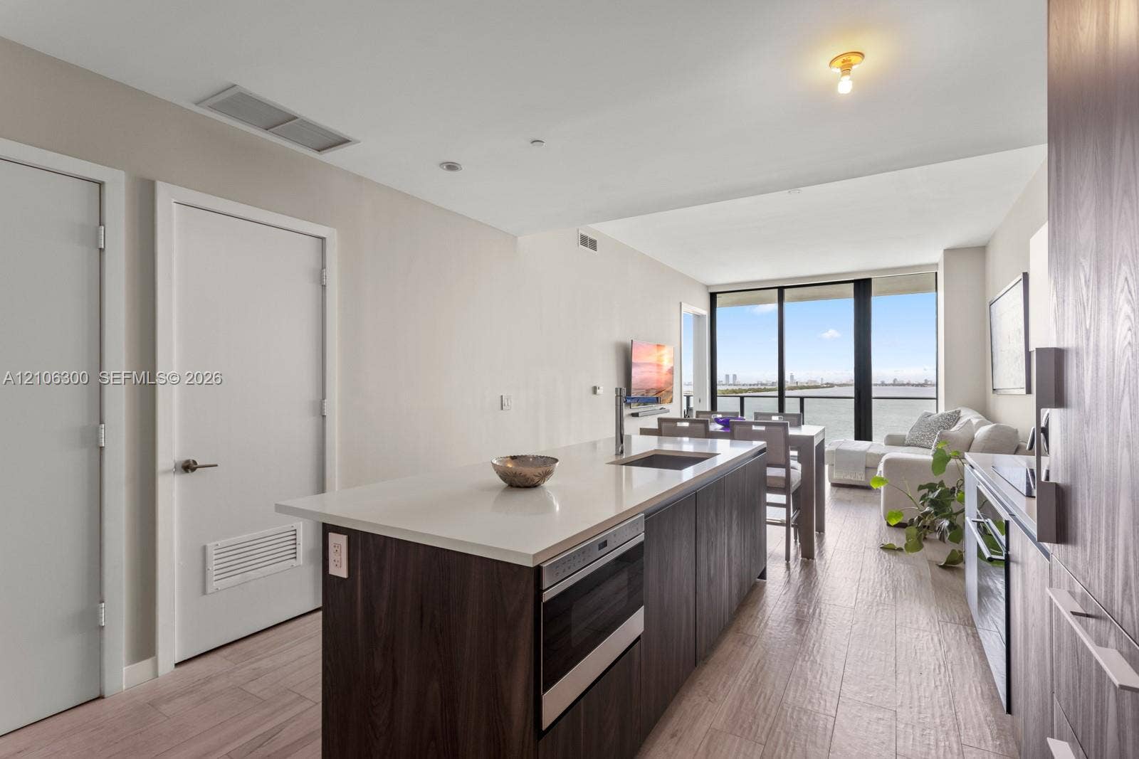 480 NE 31st Street, #1005, Miami, Miami, FL 33137 Kitchen featuring a central island with a solid surface countertop, wood-finish cabinetry, built-in microwave, wood-finish flooring, and floor-to-ceiling windows