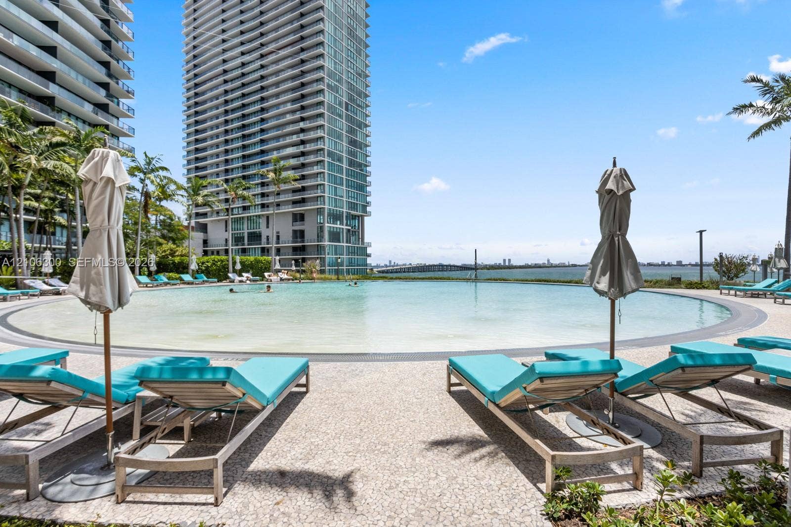 480 NE 31st Street, #1005, Miami, Miami, FL 33137 Circular swimming pool with a zero-entry edge, pebble-finish pool deck, and coastal water backdrop