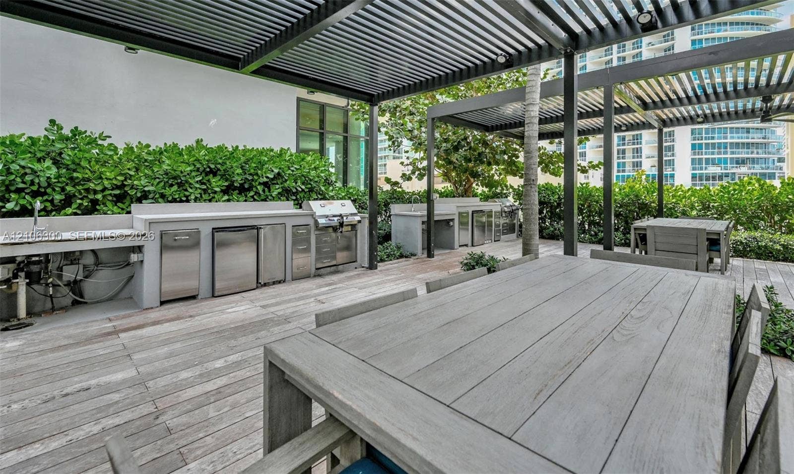 480 NE 31st Street, #1005, Miami, Miami, FL 33137 Outdoor kitchen featuring stainless steel built-in appliances, concrete-finish countertops, pergola-covered terrace, and wood-finish decking