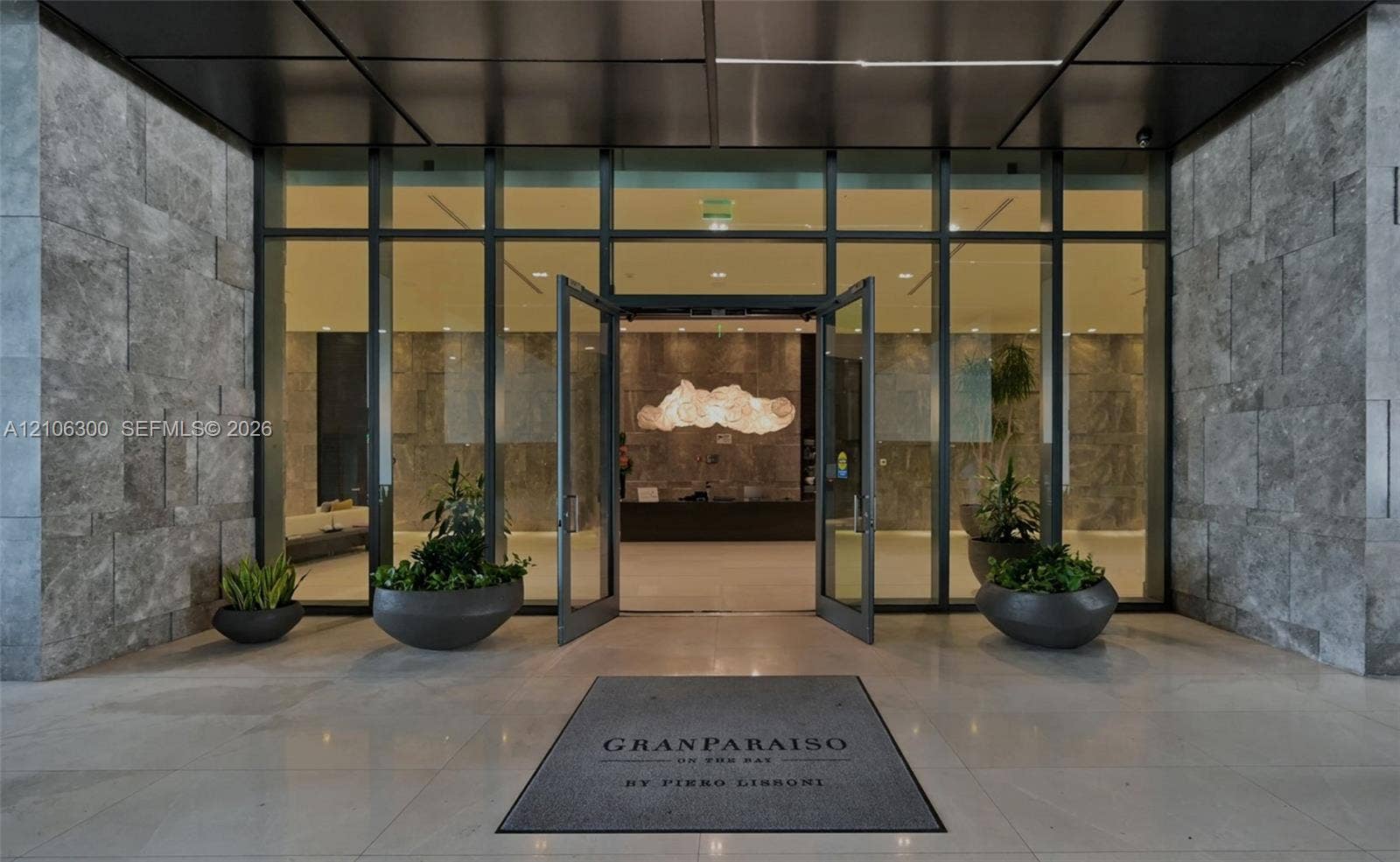 480 NE 31st Street, #1005, Miami, Miami, FL 33137 Expansive glass-paneled entrance framed by oversized textured stone cladding, polished stone flooring, and a sleek metal ceiling canopy