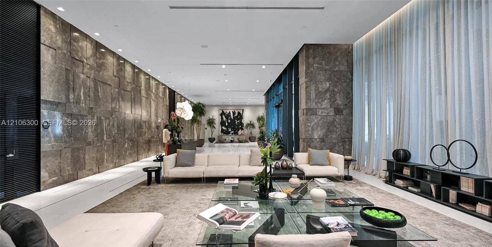480 NE 31st Street, #1005, Miami, Miami, FL 33137 Expansive interior space featuring a large-scale natural stone wall, polished stone flooring, floor-to-ceiling sheer drapery, and recessed linear lighting