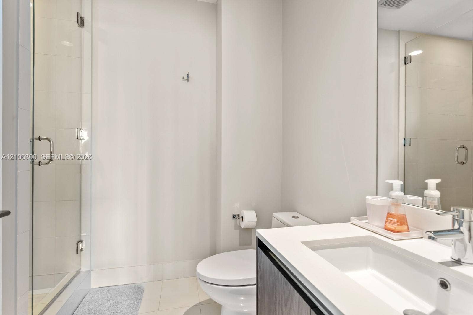 480 NE 31st Street, #1005, Miami, Miami, FL 33137 Glass-enclosed shower with tiled surround, vanity featuring an integrated sink, quartz-composite countertop, and wall-mounted mirror