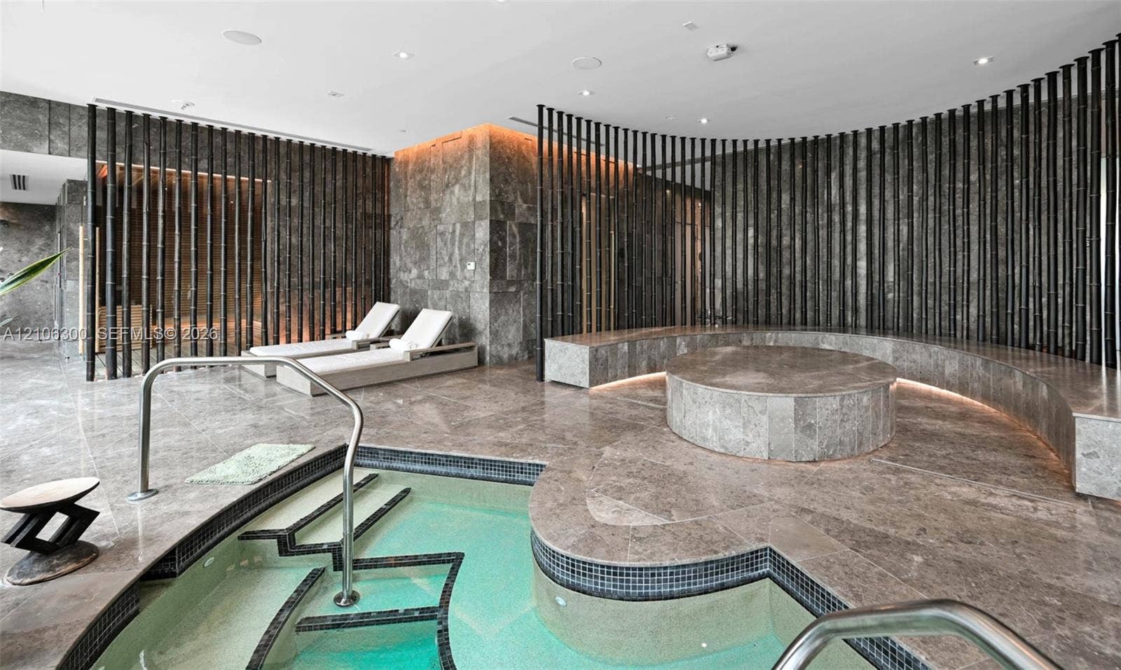 480 NE 31st Street, #1005, Miami, Miami, FL 33137 Spa area featuring stone-clad flooring and walls, curved built-in stone seating with integrated ambient lighting, circular raised stone platform, and tiled plunge pool with stainless steel handrails