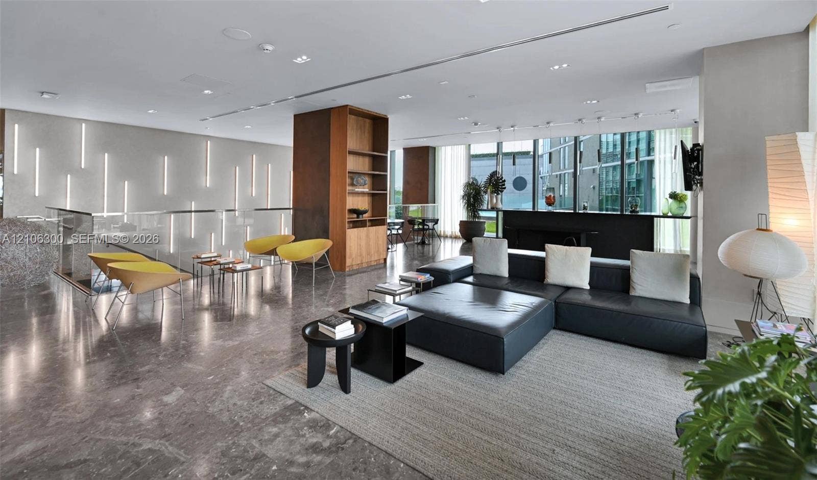 480 NE 31st Street, #1005, Miami, Miami, FL 33137 Open-concept interior featuring polished stone flooring, recessed ceiling lighting, floor-to-ceiling windows, built-in wooden shelving, and vertical wall-mounted accent lighting