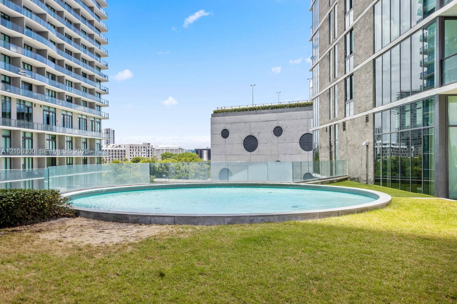 480 NE 31st Street, #1005, Miami, Miami, FL 33137 Circular outdoor pool featuring a glass balustrade surround and lawn landscaping