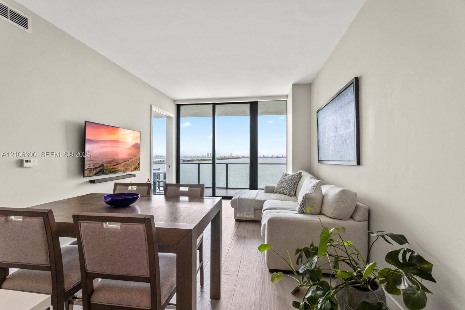 480 NE 31st Street, #1005, Miami, Miami, FL 33137 Living area with wood-finish flooring, floor-to-ceiling glass sliding doors, and a covered balcony overlooking the water