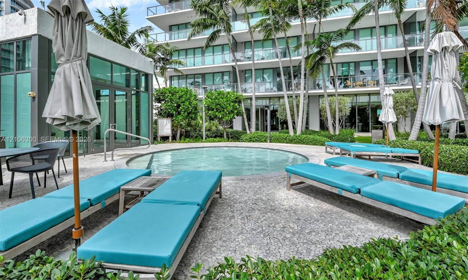 480 NE 31st Street, #1005, Miami, Miami, FL 33137 Circular swimming pool surrounded by a stone-paved deck, landscaped garden beds, and palm trees