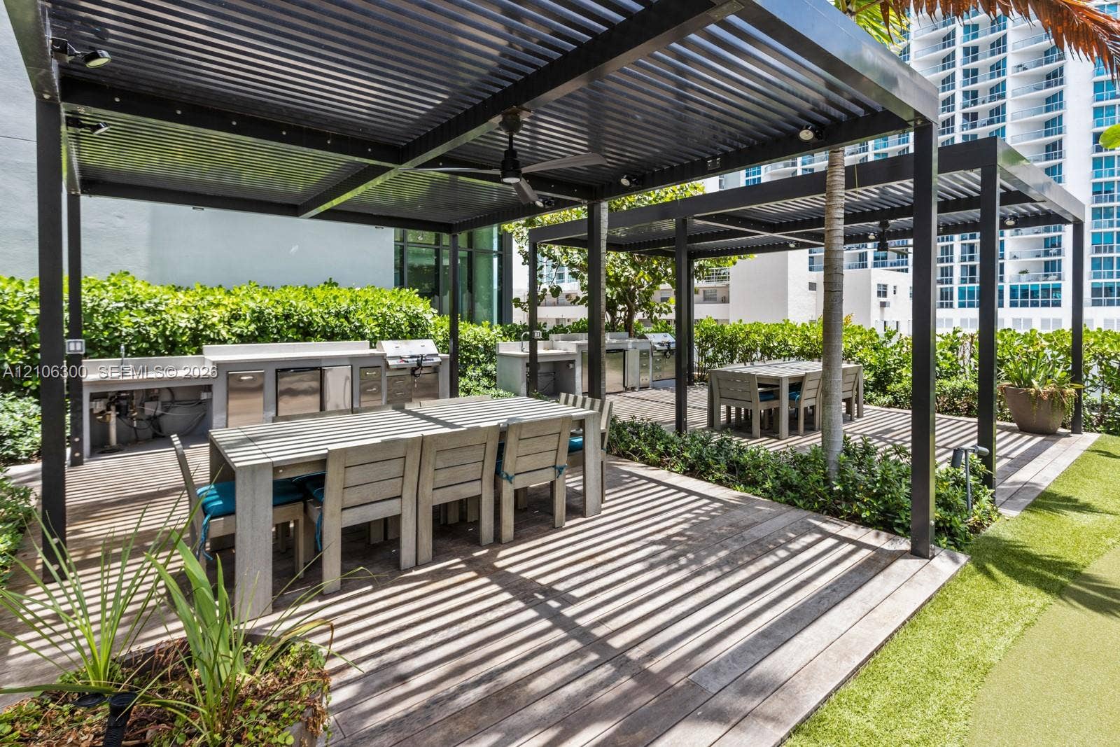 480 NE 31st Street, #1005, Miami, Miami, FL 33137 Outdoor kitchen featuring stainless steel appliances, dual metal pergolas, wood-finish decking, and built-in stone-finish counters