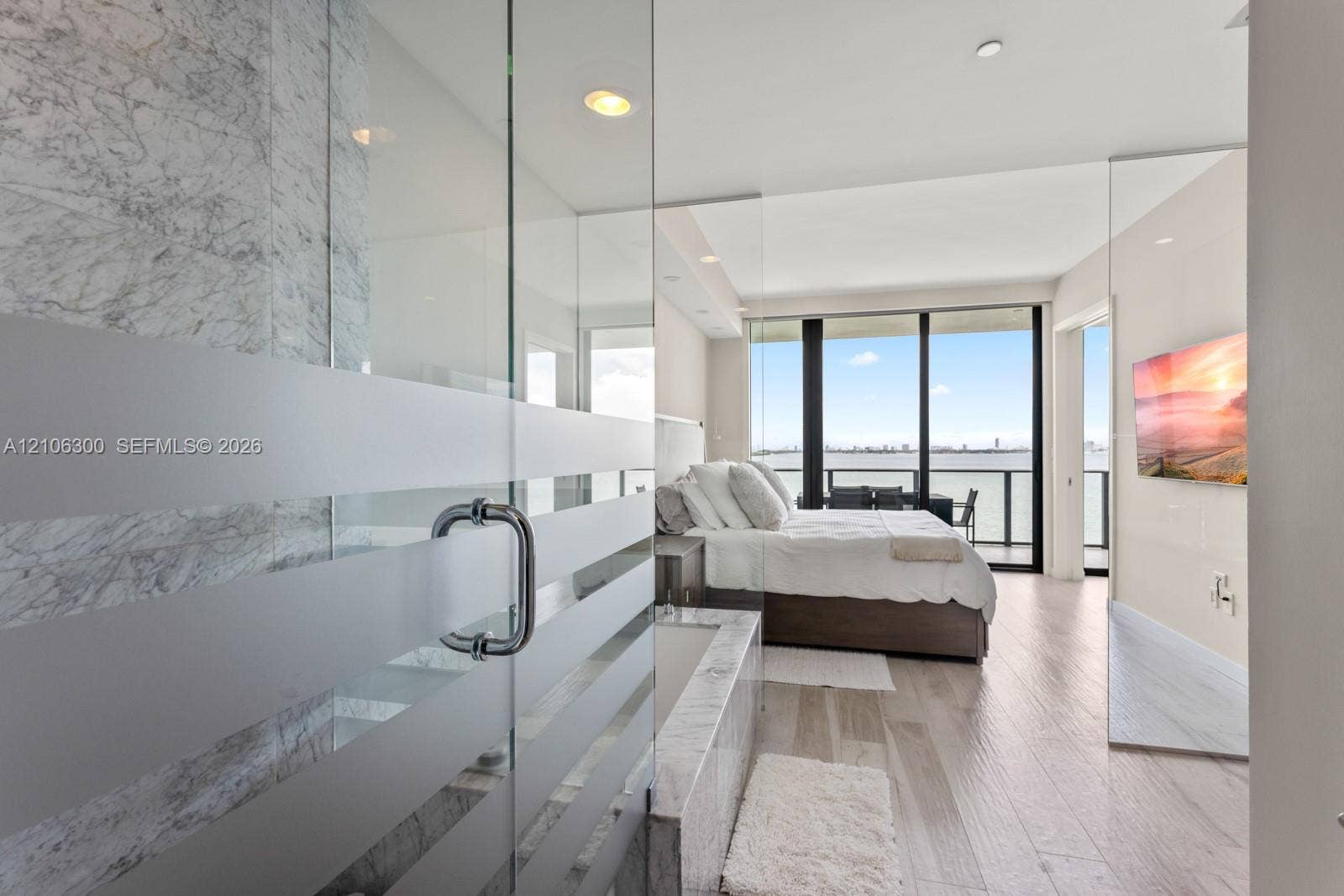 480 NE 31st Street, #1005, Miami, Miami, FL 33137 Floor-to-ceiling windows, stone-clad soaking tub, glass-enclosed shower with frosted detailing, wood-finish flooring, and recessed lighting