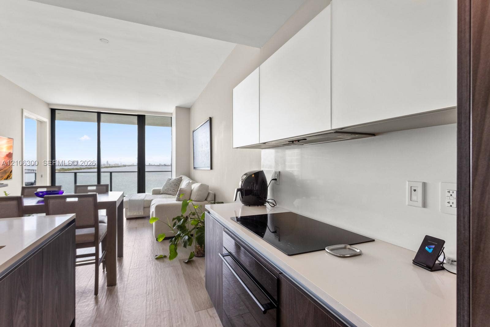480 NE 31st Street, #1005, Miami, Miami, FL 33137 Modern kitchen featuring flat-panel cabinetry, light-toned countertops, a glass-ceramic cooktop, and wood-finish flooring with floor-to-ceiling windows