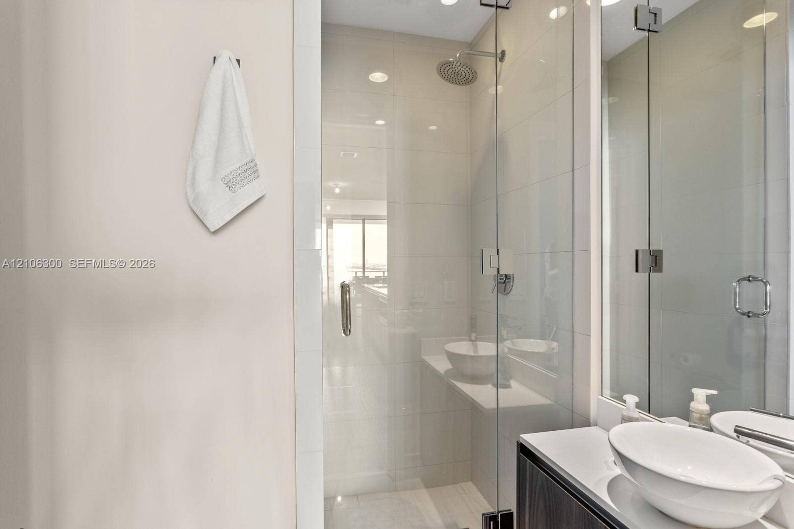 480 NE 31st Street, #1005, Miami, Miami, FL 33137 Walk-in shower with floor-to-ceiling tile, frameless glass enclosure, and a ceiling-mounted rainfall showerhead, accompanied by a floating vanity featuring dual vessel sinks and polished countertops