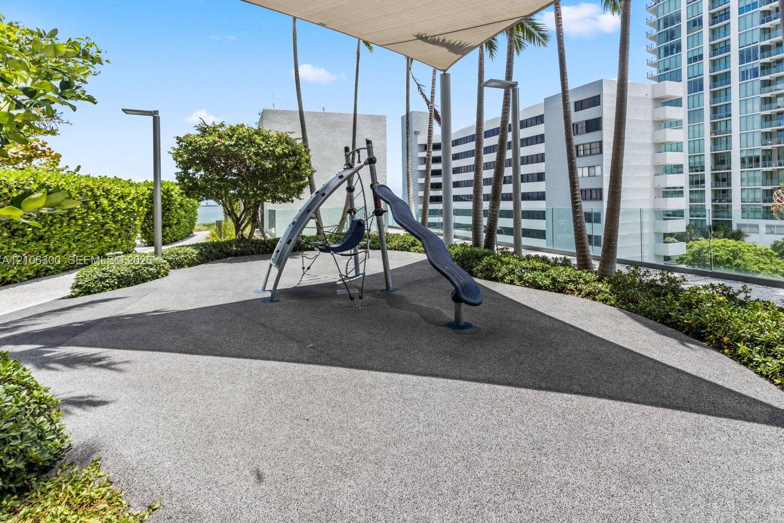 480 NE 31st Street, #1005, Miami, Miami, FL 33137 Outdoor recreation area featuring a play structure with a slide, rubberized surfacing, overhead shade canopy, perimeter landscaping, and vertical lighting fixtures